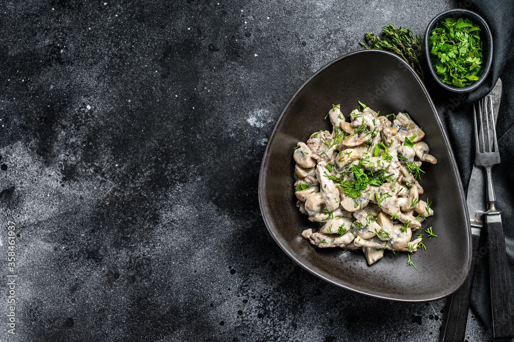 Beef Stroganoff with mushrooms and fresh parsley in a plate. Black background. Top view. Copy space