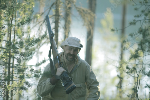 man goes hunting forest summer / landscape in the forest, huntsman with a hunting rifle hunts