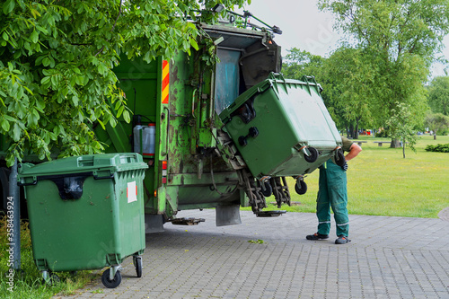 Fotografie Municipal cleaning service workers remove waste with a garbage truck