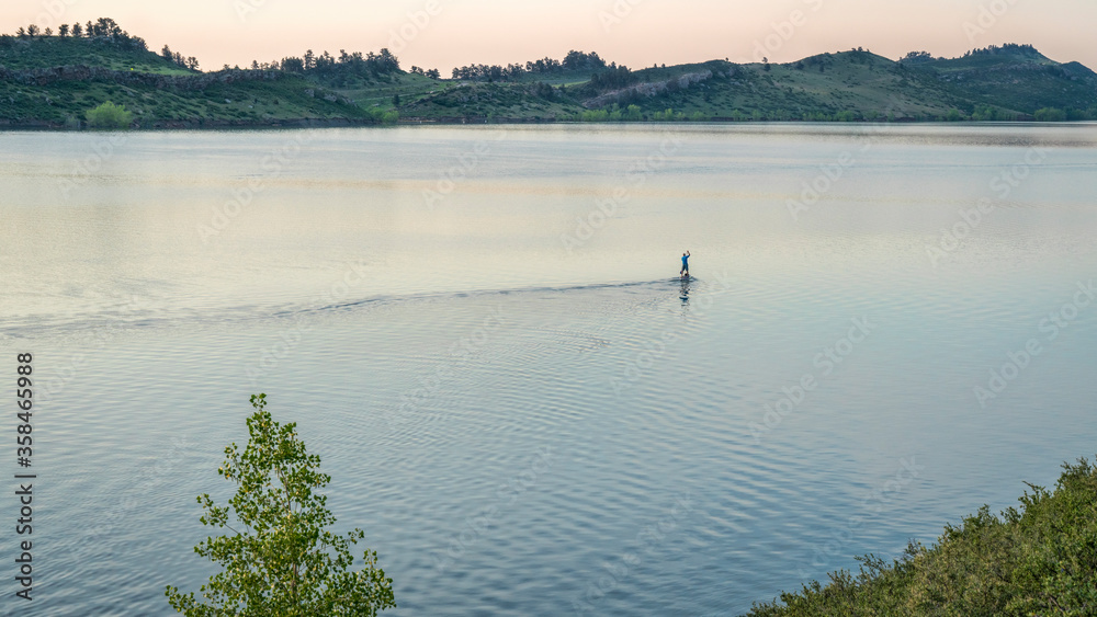 summer dawn over mountain lake with a lonely SUP paddler - Horsetooth Reservoir at foothills of Rocky Mountains in northern Colorado, popular recreation destination in Fort Collins area