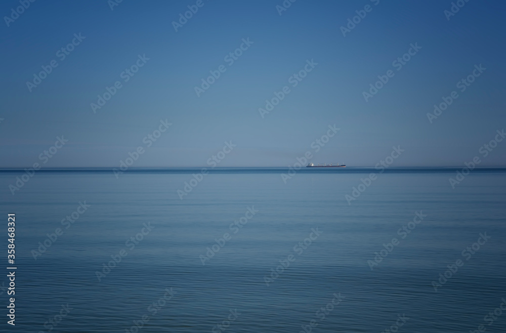 Ship on the horizon against the blue sea and sky Ship on the horizon against the blue sea and sky