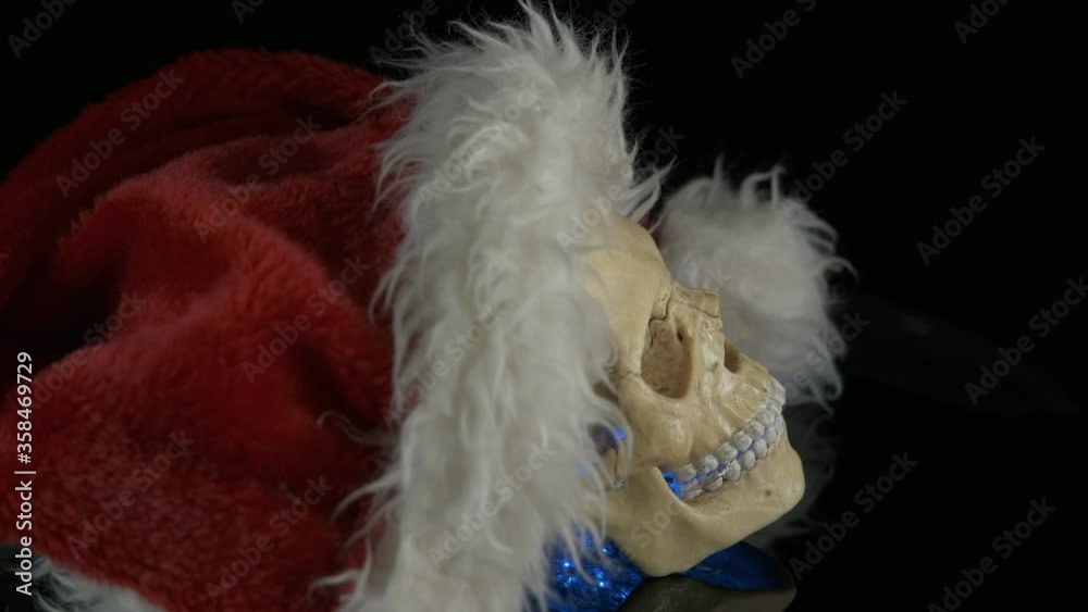 Garland in the mouth. Skull wearing a santa claus hat. Scary Christmas. Garland in the mouth. Skull wearing a santa claus hat. Scary Christmas.