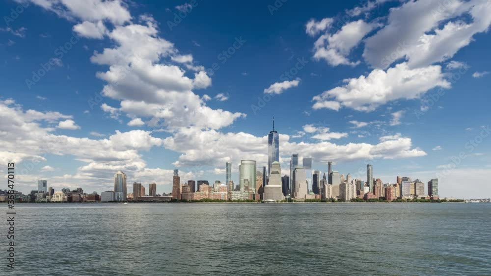 Time lapse of white clouds flying in blue sky over Downtown Manhattan skyline on bright sunny day in June of 2020.