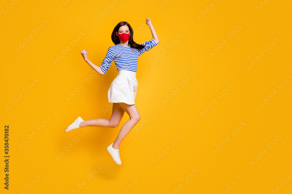 Yes we stop covid. Full body photo of ecstatic girl jump raise fists wear medical mask blue white striped shirt short mini skirt legs isolated over bright shine color background