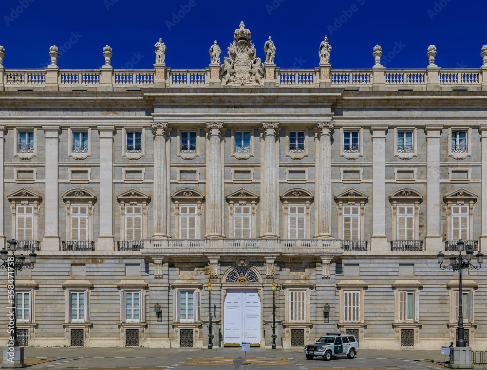 Ornate baroque architecture of the Royal Palace viewed from Plaza de Oriente and police car outside in Madrid, Spain