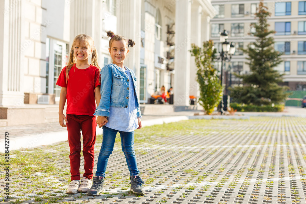 Portrait of happy fashion little girls having fun in the city