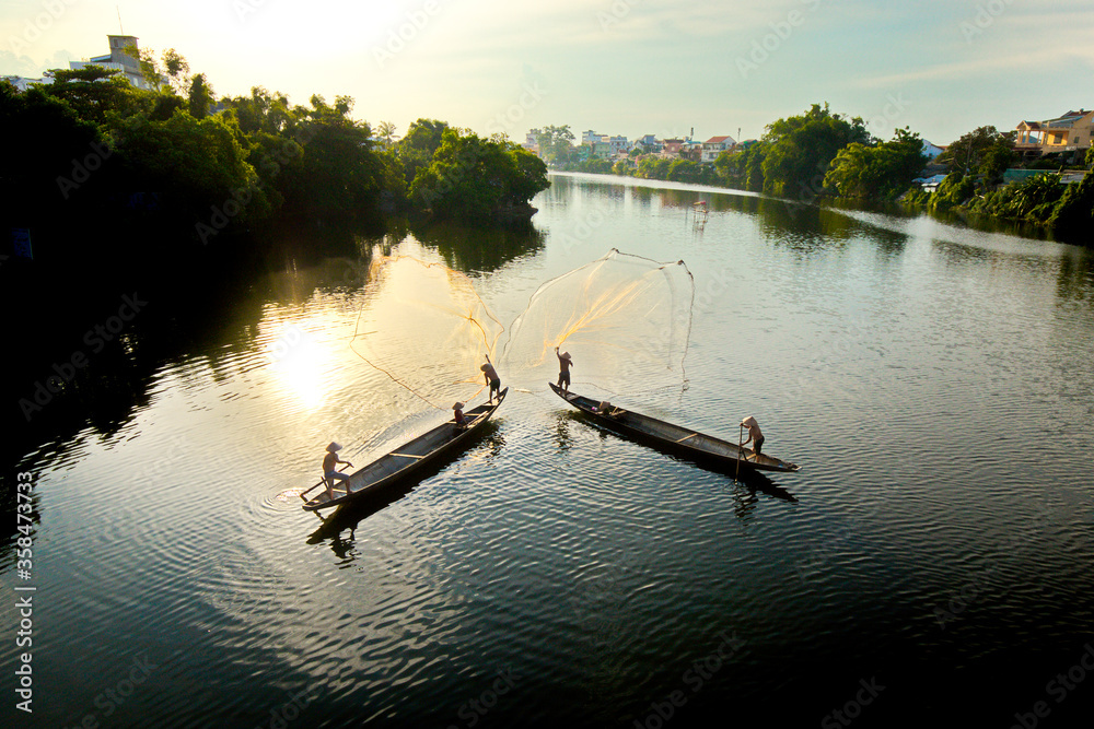 HUE CITY, VIETNAM - JUNE 13, 2020: Unidentified fishermen casting fishing nets on Nhu Y river. Fishing has become their traditional career for hundreds of years.