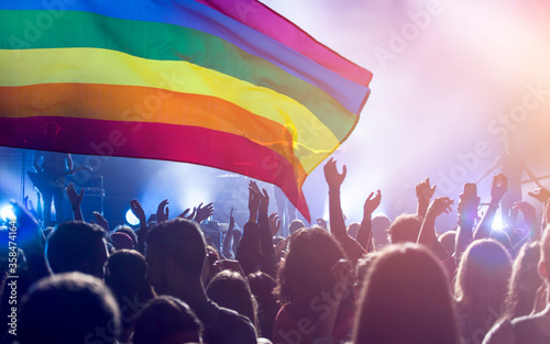 Colorful LGBT flag blows in the breez over crowd. photo