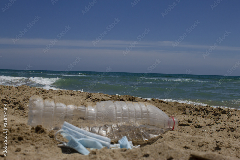 Beach pollution and garbage in Mediterranean Sea .Used dirty plastic bottle and medical mask against coronavirus . Empty place for text.(Environment concept) Beach pollution and garbage in Mediterranean Sea .Used dirty plastic bottle and medical mask against coronavirus . Empty place for text.(Environment concept)