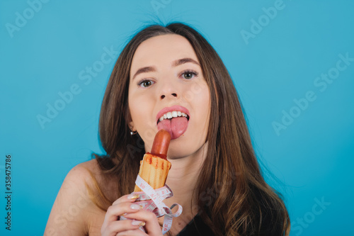 girl holds hot dog in hand with measuring tape on blue background