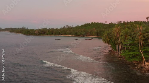 Drone revealing a small bay with boats and resorts on a small tropical island in Northern Mentawai. photo