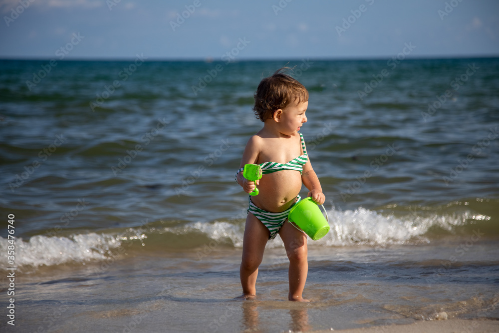 little cheerful happy baby boy plays in the waves of the sea with a bucket and a shovel little cheerful happy baby boy plays in the waves of the sea with a bucket and a shovel