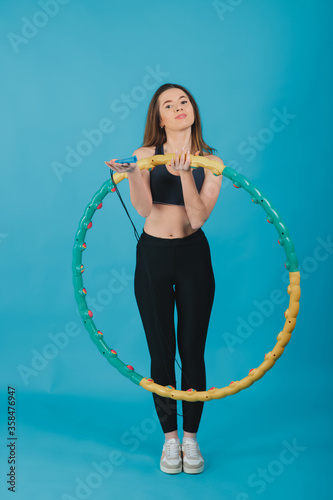 cheerful sport girl with hula hoop on blue background