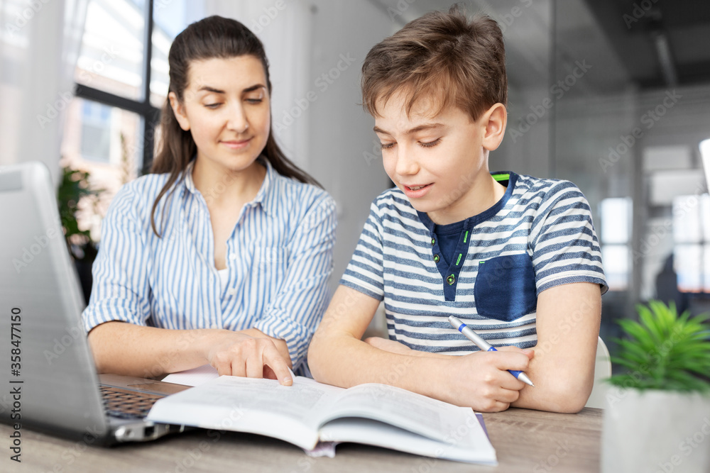 education, family and homework concept - mother and son with book writing to notebook at home education, family and homework concept - mother and son with book writing to notebook at home