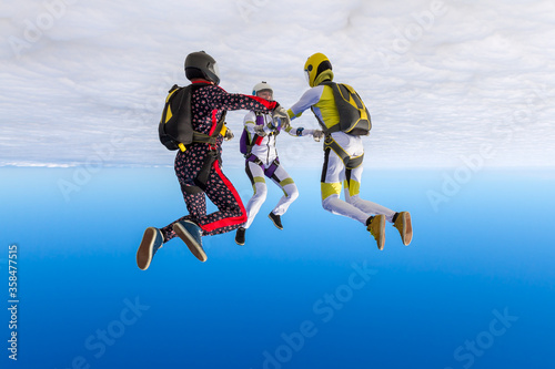 Skydiving photo. Three sports parachutist build a figure in free fall. Extreme sport concept.