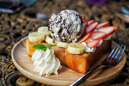 Honey Toast on top with Chocolatchip Ice Cream and a lot of fruit , fresh banana,slice of strawberry and whip cream photo