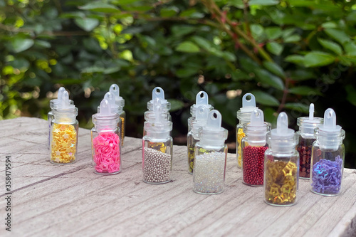 Colorful glitters for nail art and makeup in small glass jars isolated