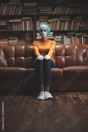 Woman with protective antiviral mask sitting at home in isolation / quarantine.