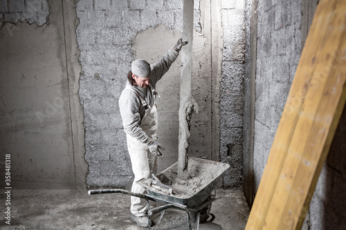 Real construction worker making a wall inside the new house.