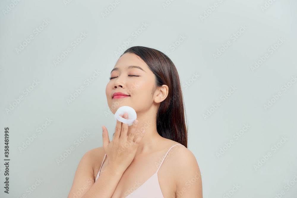 Young lady applying blusher on her face with powder puff, skin care concept Young lady applying blusher on her face with powder puff, skin care concept
