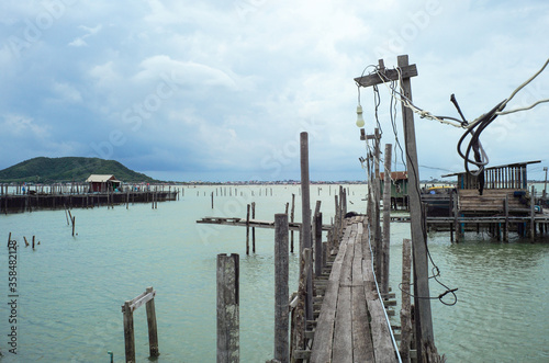 Native fisherman house and traditional fishing farm at the coast of sea with old wooden walkway © Phichat