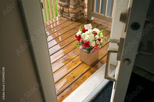 Photography A bouquet of red white flowers in a carton box on a porch doorstep of a house