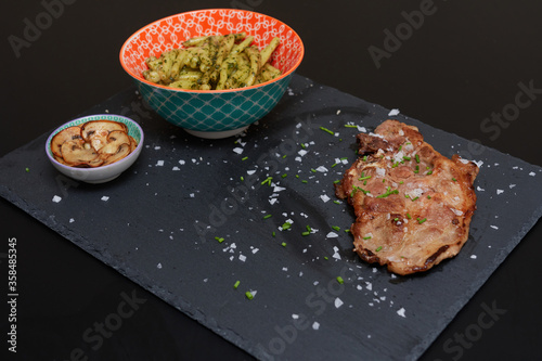 head of pork loin, in a bowl pasta with pesto on a blackboard photo