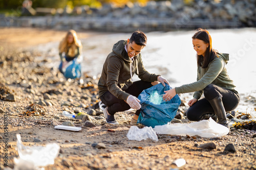 Team of dedicated and smiling volunteers collecting garbage at beach © kjekol