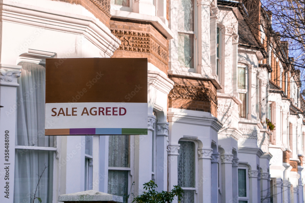  'SALE AGREED' estate agent sign  and row of British terraced houses