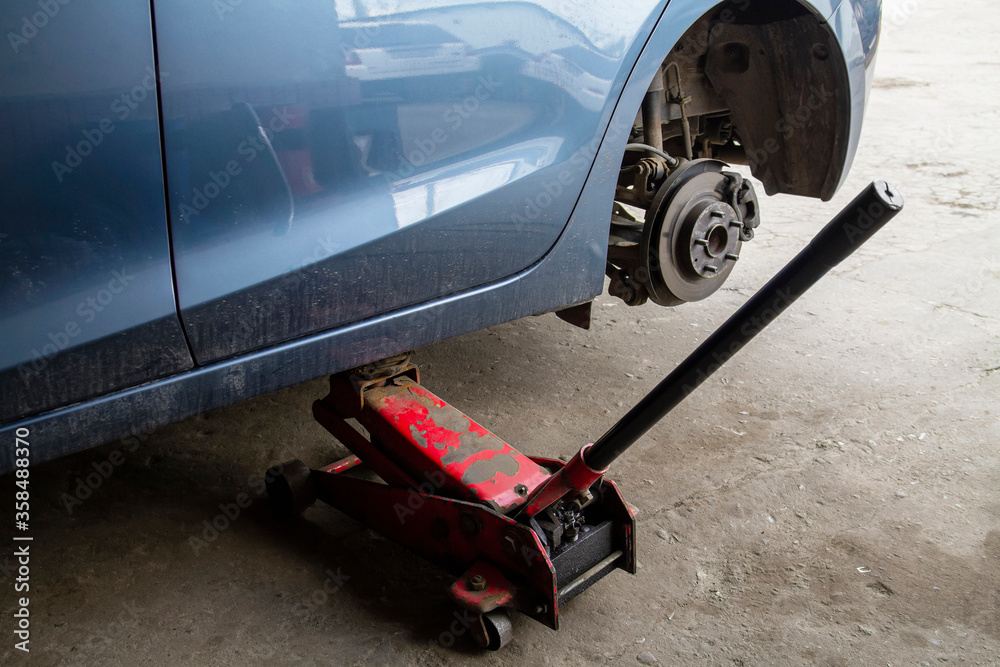 Replacing wheels on a car, jack holds the body in raised position. Car