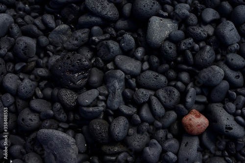 Una piedra roja o marrón en contraste con un fondo de piedras negras.