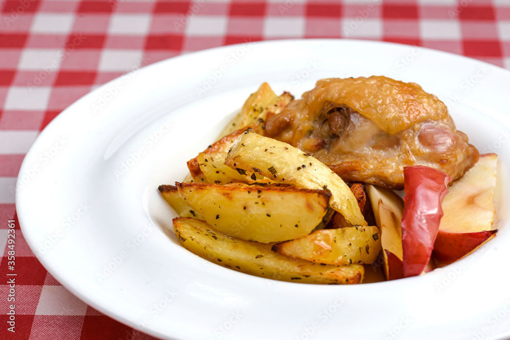 Fried potatoes with meat and baked apples. Tasty dinner. Served in a white plate over red plaid tablecloth.