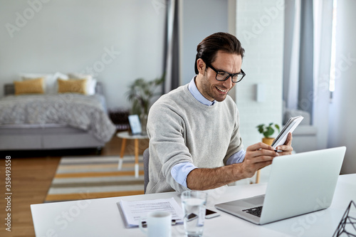 Young happy businessman using laptop while working at home.