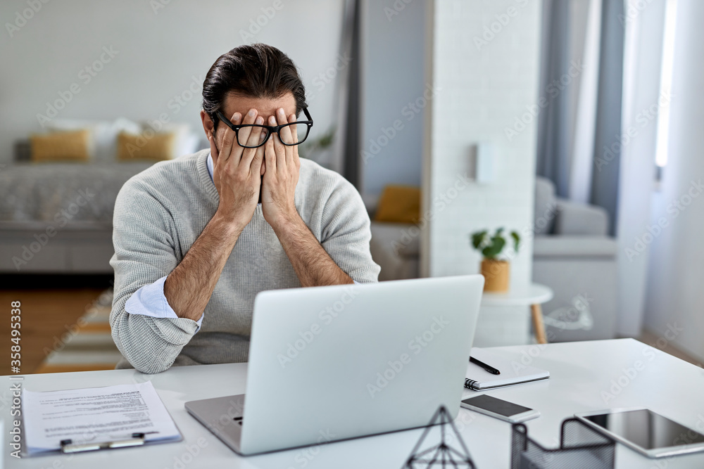 Tired male entrepreneur working on a computer at home.