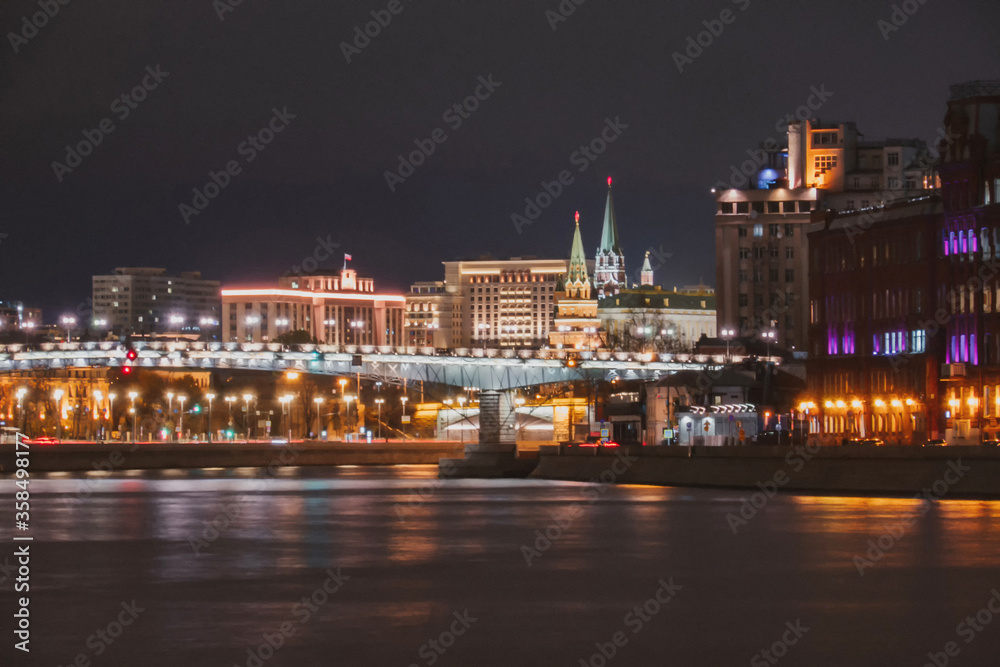 Illuminated Moscow bridge across the Moskva river at evening or night with city lights.