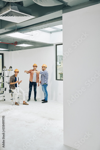 Vertical long shot image depicting typical workday routine of modern professional construction engineers, copy space © DragonImages
