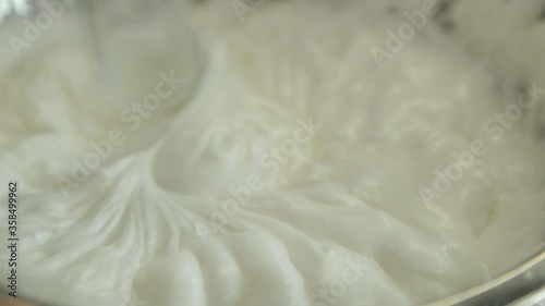 Whipping white cream with a mixer in slow motion. Dessert Pavlova.