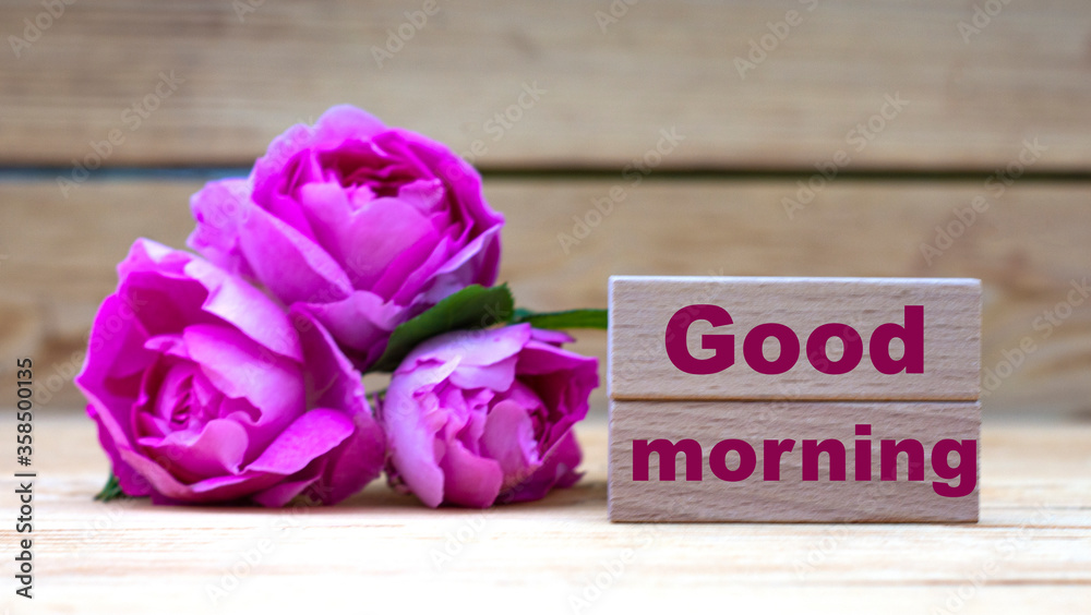 GOOD MORNING - words on wooden blocks on a light background with pink roses