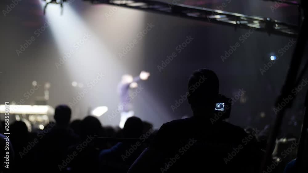 Video operator crane is shooting a crowd of people around the stage. Camcorder for shooting rock music concerts. Long boom crane. Self-isolation mode is over. Music band is playing on stage. Video operator crane is shooting a crowd of people around the stage. Camcorder for shooting rock music concerts. Long boom crane. Self-isolation mode is over. Music band is playing on stage.