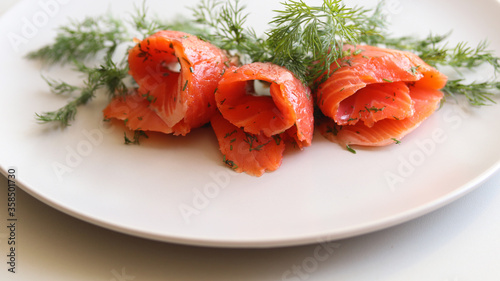 salmon slices and dill on a white plate on a white background close up