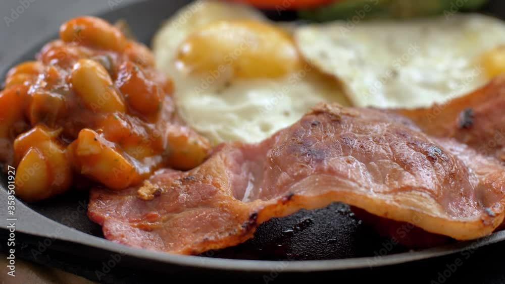 Breakfast, fried eggs with sausages, green beans, tomatoes. Serving on a wooden table in a restaurant. Closeup. Breakfast, fried eggs with sausages, green beans, tomatoes. Serving on a wooden table in a restaurant. Closeup.