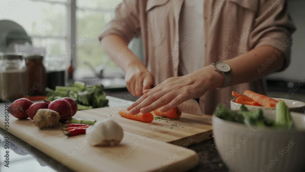 Close-up of a girl food blogger cutting the carrots on chopping board at home in kitchen during lockdown period