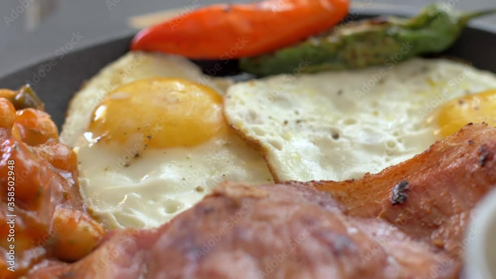 Breakfast, fried eggs with sausages, green beans, tomatoes. Serving on a wooden table in a restaurant. Closeup. Breakfast, fried eggs with sausages, green beans, tomatoes. Serving on a wooden table in a restaurant. Closeup.