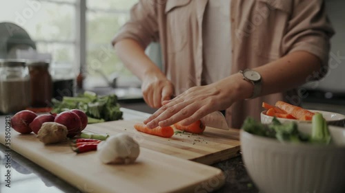 Close-up of a girl food blogger cutting the carrots on chopping board at home in kitchen during lockdown period