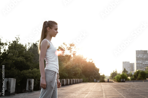 confident athlete girl standing outdoor on the morning sunrise and preparing doing exercise © darakaliton
