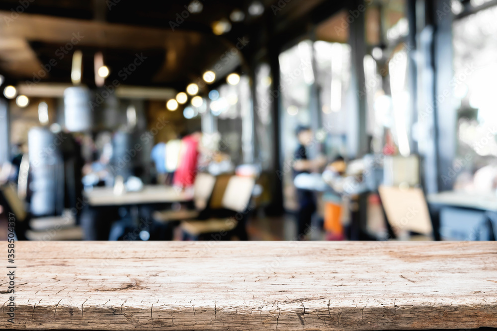 Empty wooden desk space platform over blurred restaurant or coffee shop background for product display montage.