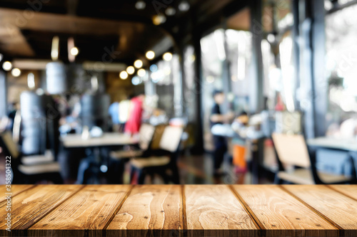 Empty wooden desk space platform over blurred restaurant or coffee shop background for product display montage.