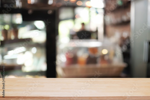 Empty wooden desk space platform over blurred restaurant or coffee shop background for product display montage.