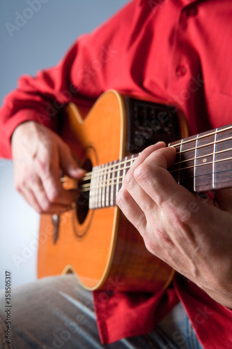 Fingers of a guitar player playing acoustic guitar.