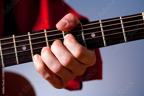 Fingers of a guitar player playing acoustic guitar.